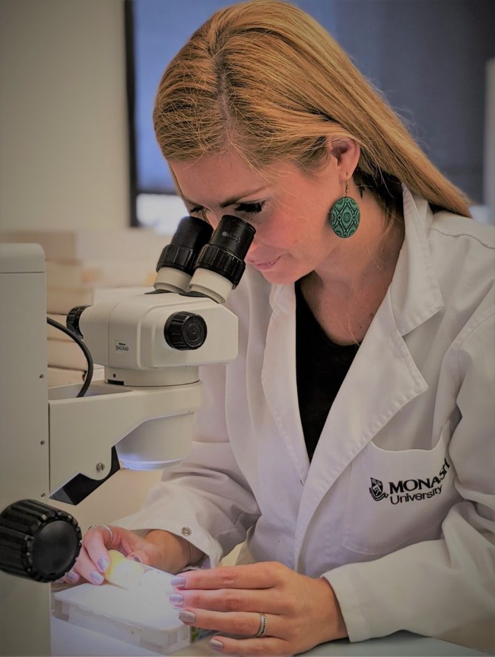 Tara-Lyn Camilleri examining flies under the microscope